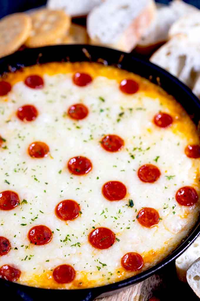 A cast iron skillet filled with hot and gooey pizza dip topped with mini pepperoni.