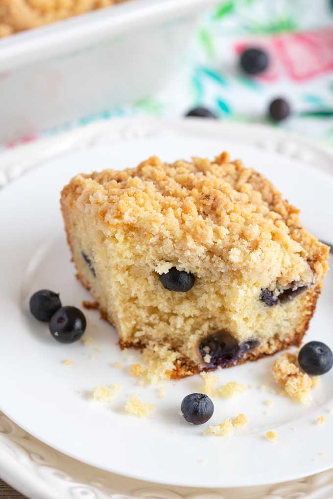 A slice of blueberry coffee cake on a white plate.