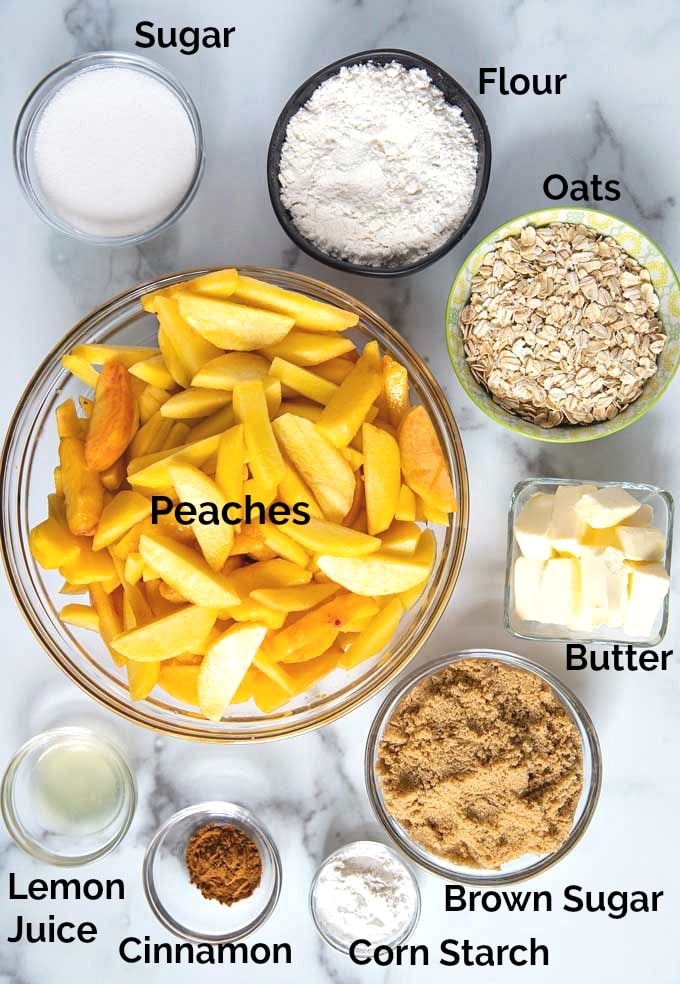 Ingredients to make peach crisp on a marble surface.
