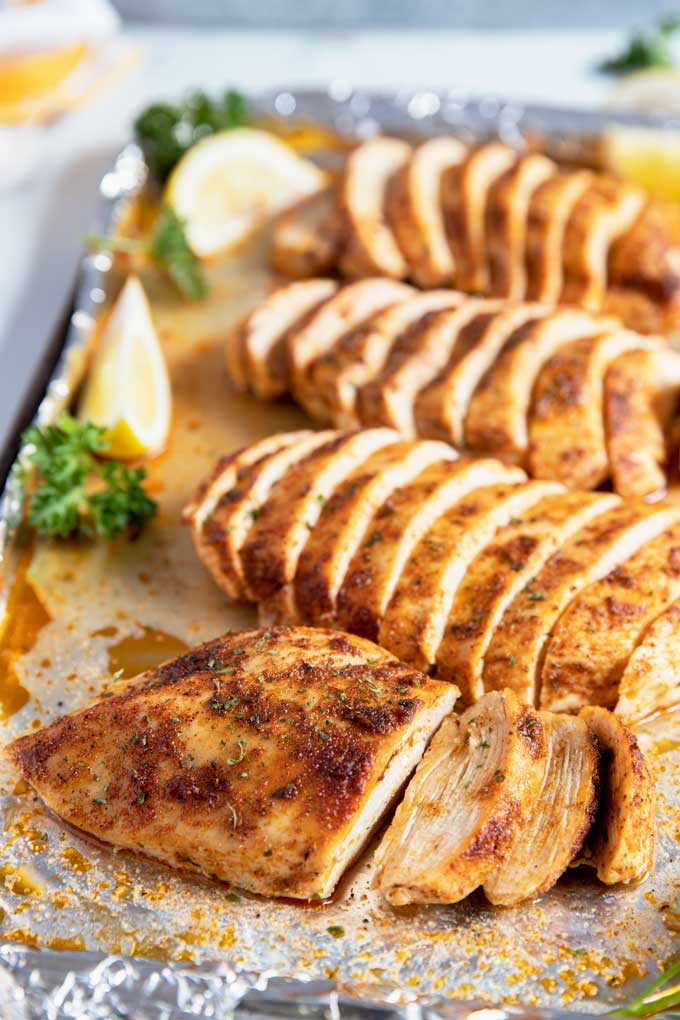 Sliced baked chicken breasts on a baking sheet