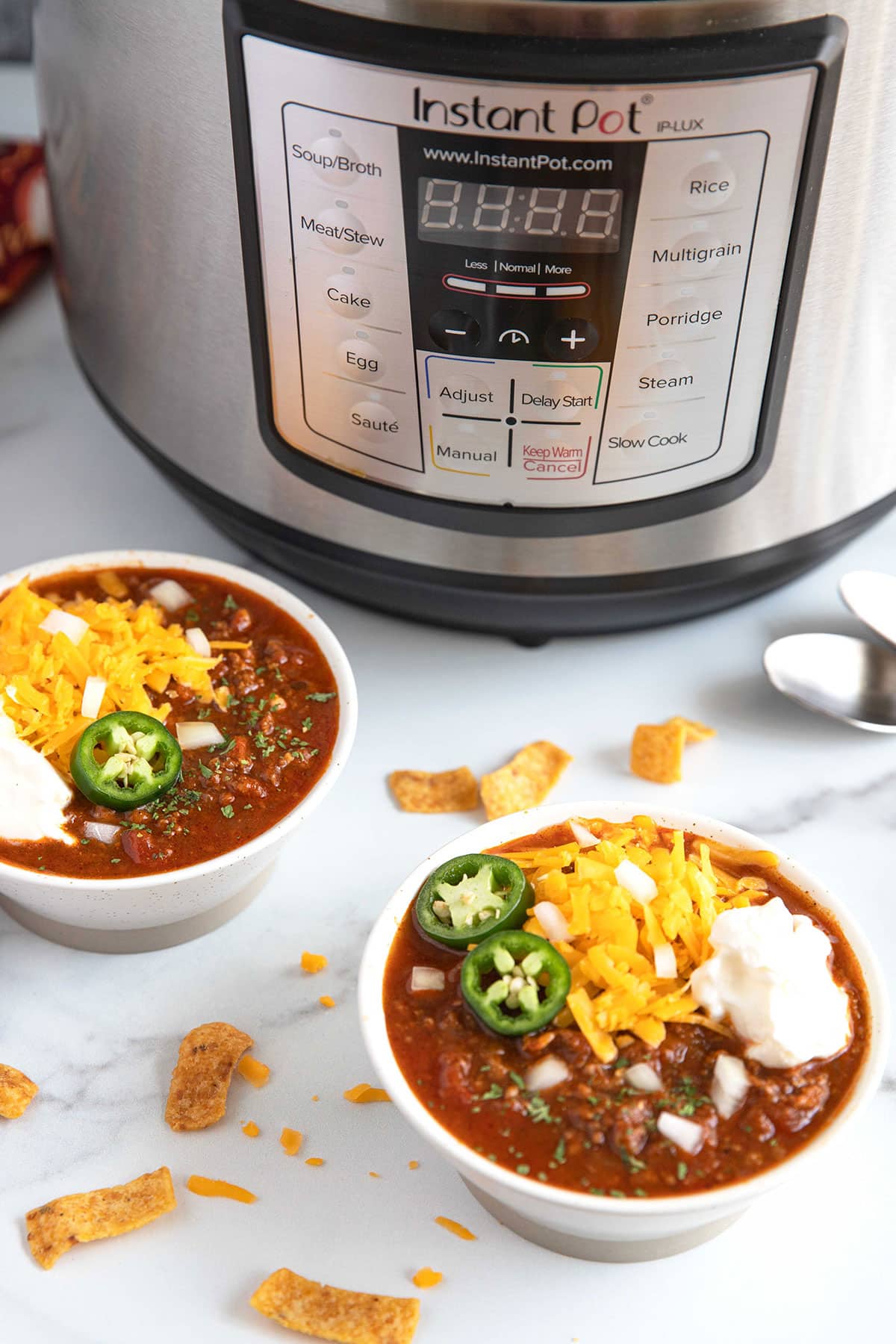 Bowls of chili sitting next to an Instant Pot pressure cooker.
