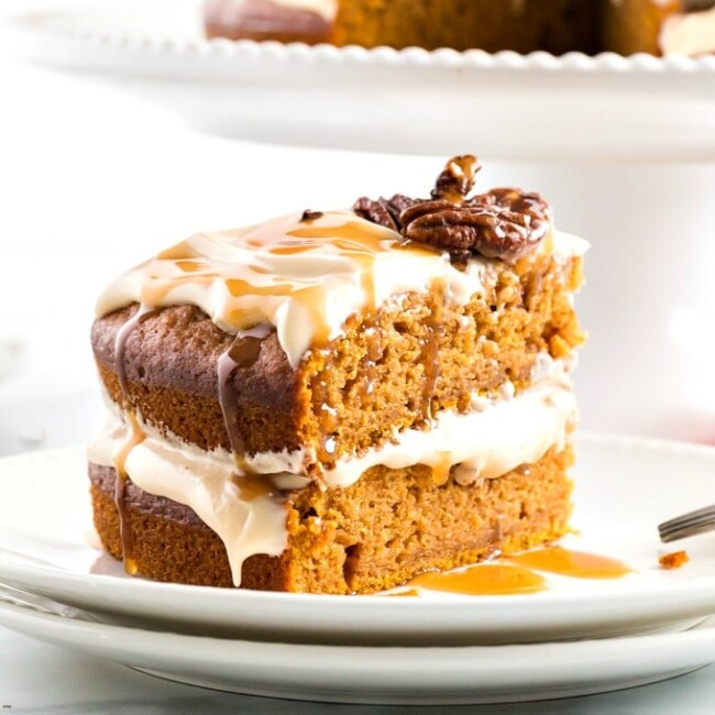 Sliced pumpkin cake with caramel cream cheese frosting on a white plate