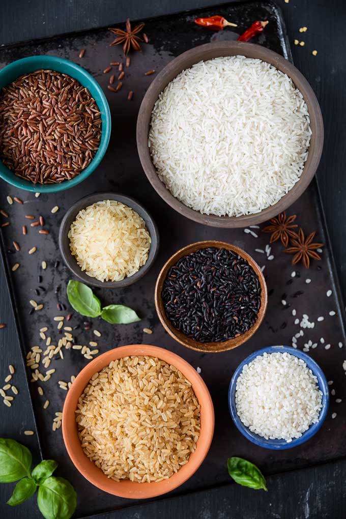 Bowls of different types of rice and rice grains. 