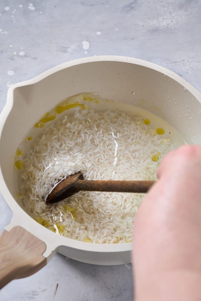 Stirring rice, water and oil in a saucepan
