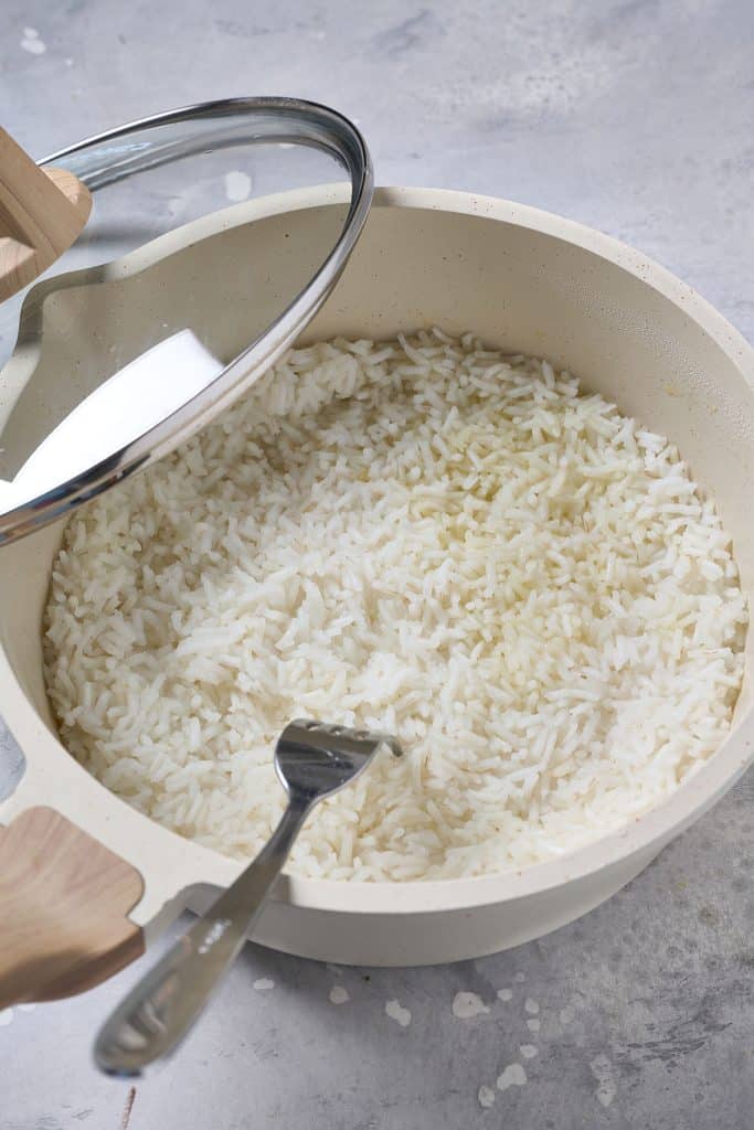 Opening the lid of a pot of steamed rice