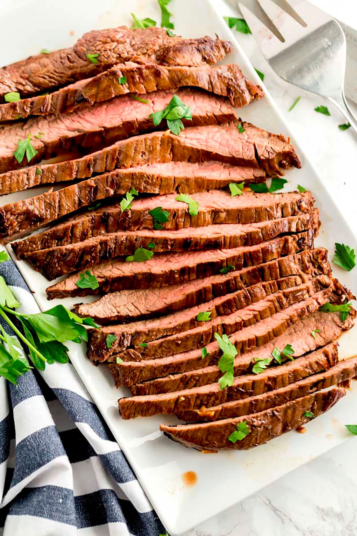  Geschnittenes saftiges und zartes London Broil Fank Steak auf einer weißen Platte.