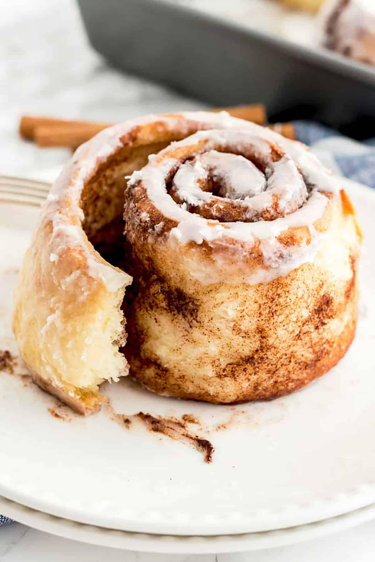 A cinnamon bun served on a plate showing it's cinnamon sugar filling.