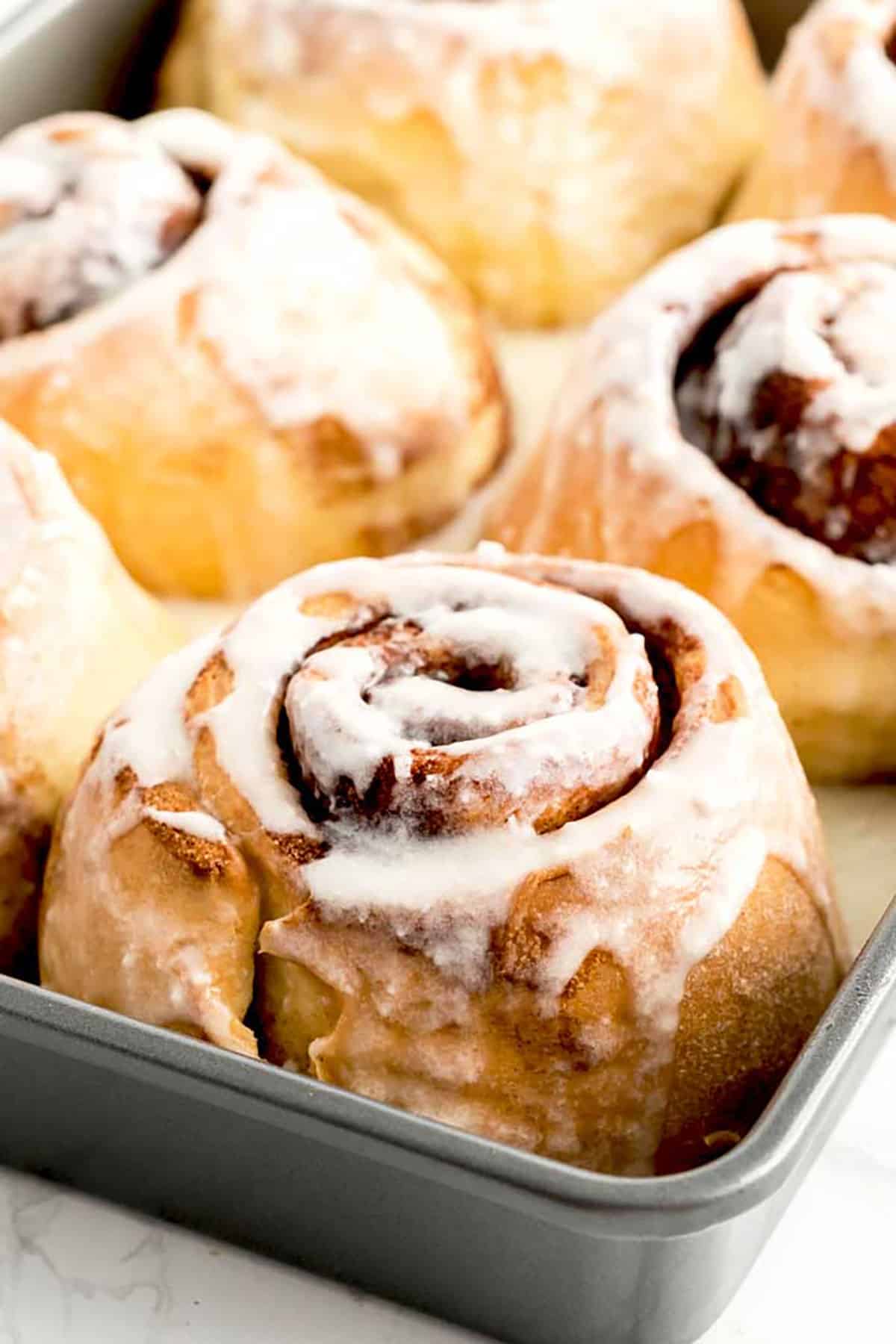 Close up of baked cinnamon buns in a baking pan.