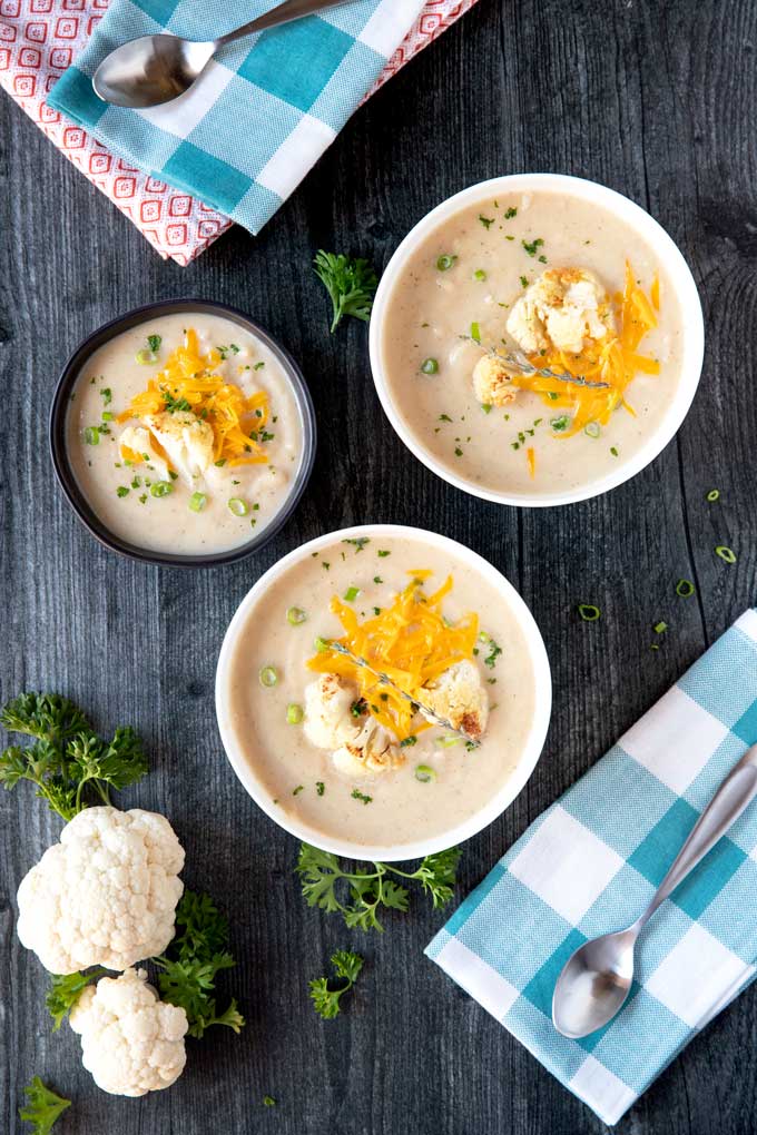 Top view of three bowls filled with creamy cauliflower soup.