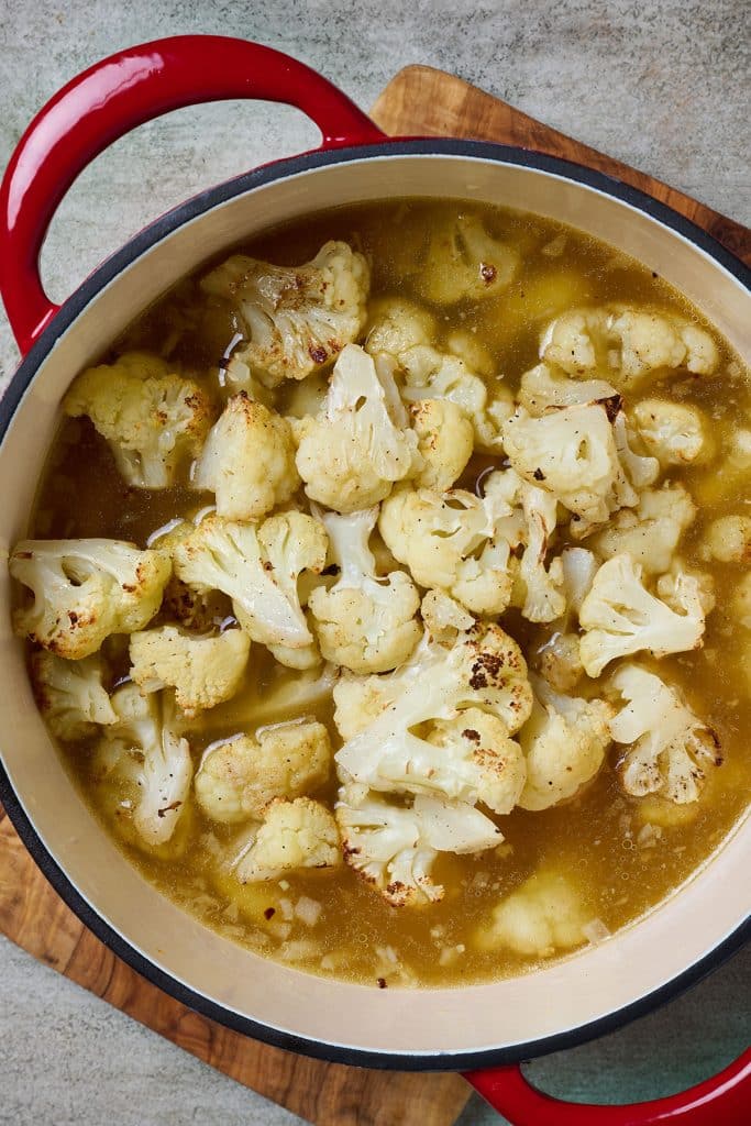 Oven roasted cauliflower added into large soup pot with other ingredients 