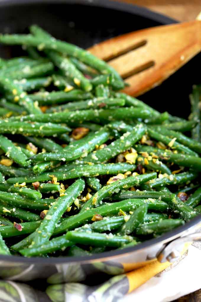 close up view of Sauteed green beans with pistachios served in a black bowl.