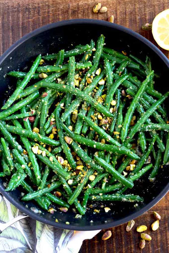 top view of Sauteed green beans with pistachios served in a black bowl.