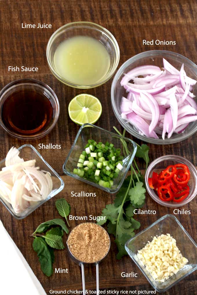 Chicken larb recipe ingredients on a wooden surface.