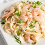 Cajun Shrimp in creamy Alfredo sauce tossed with fettuccini pasta on a white plate