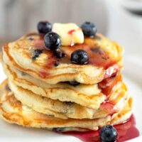 Fluffy Blueberry Pancakes Stacked up and drizzled with blueberry syrup.
