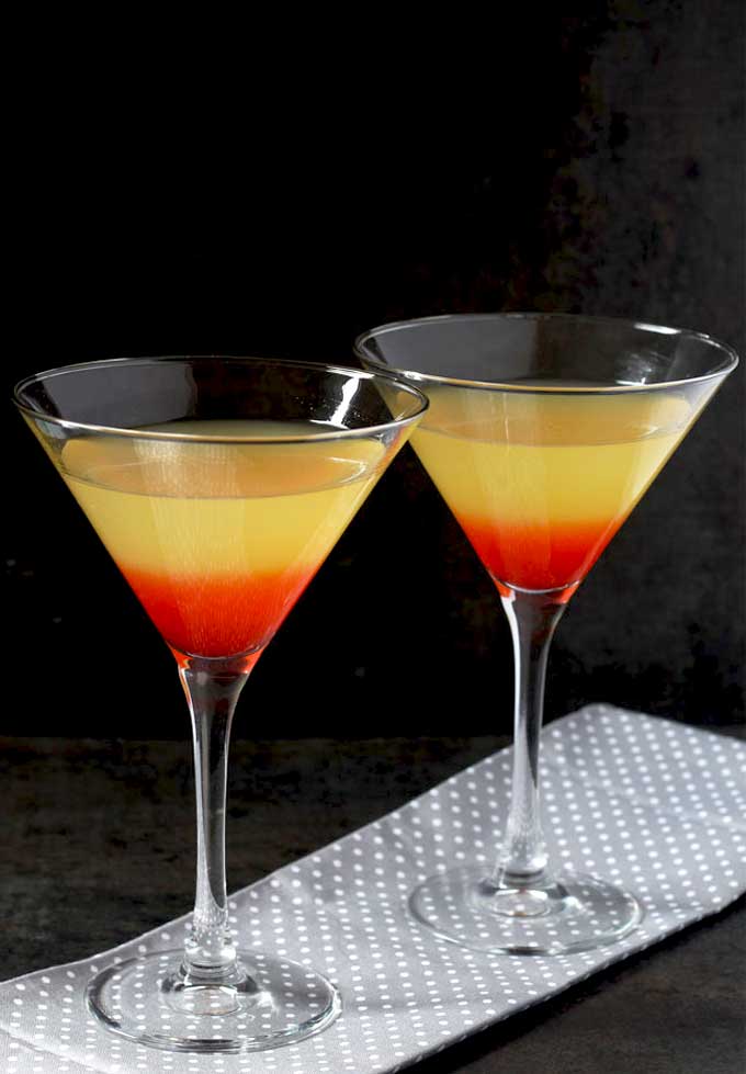 Layered cocktail in martini glassed on a gray cloth
