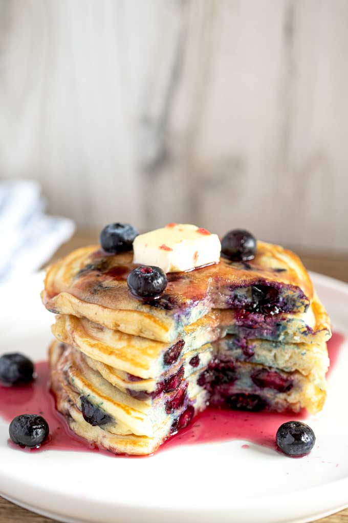 Blueberry Buttermilk Pancakes served  with blueberries and syrup and cut up ready to eat.