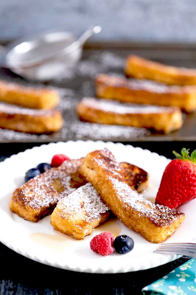 French Toasts Sticks served on a white plate and dusted with powdered sugar. 