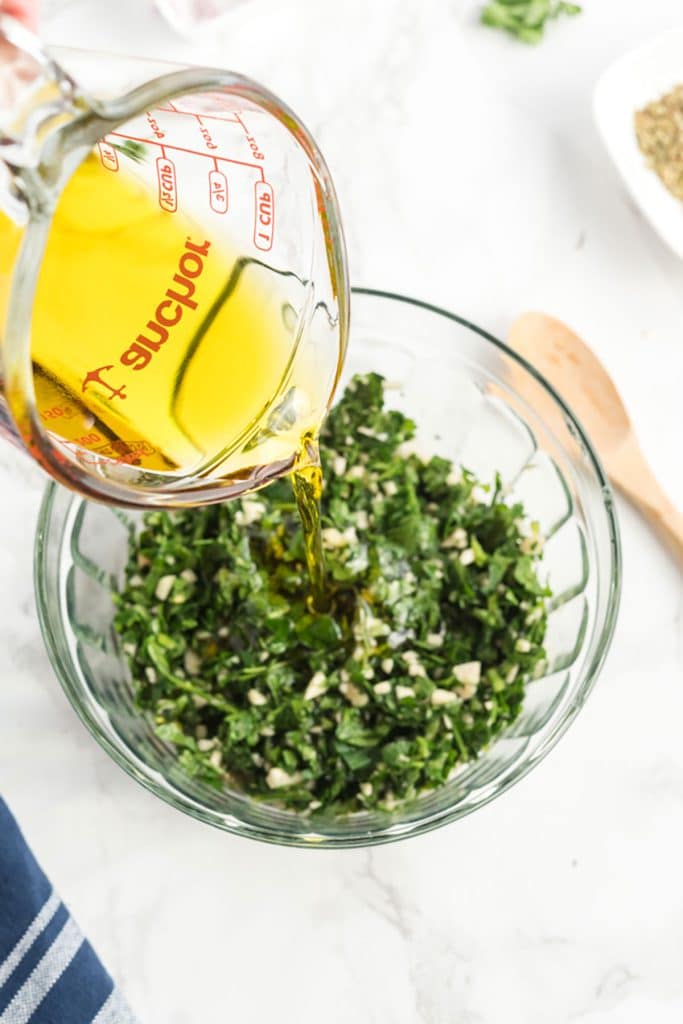 adding oil to the chimichurri mixture