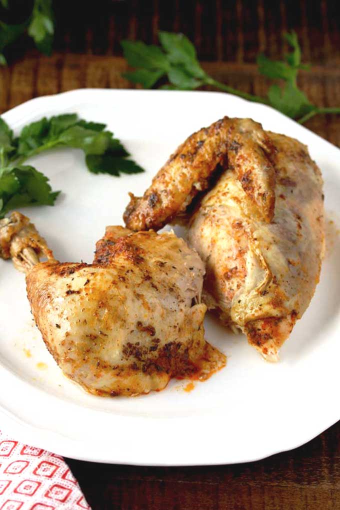 Tender and golden brown rotisserie chicken pieces on a white plate.