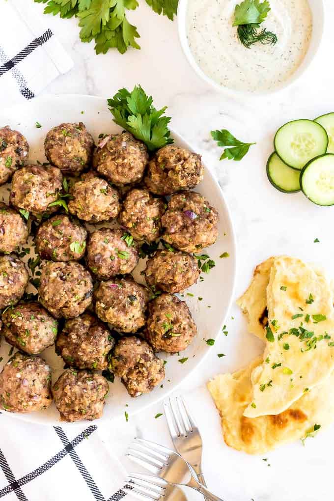 Plate filled with baked meatballs on a white surface,