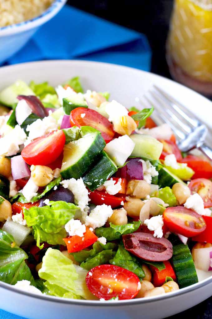 Crisp Chopped Greek Salad with Kalamata olives and Feta cheese on a white bowl.