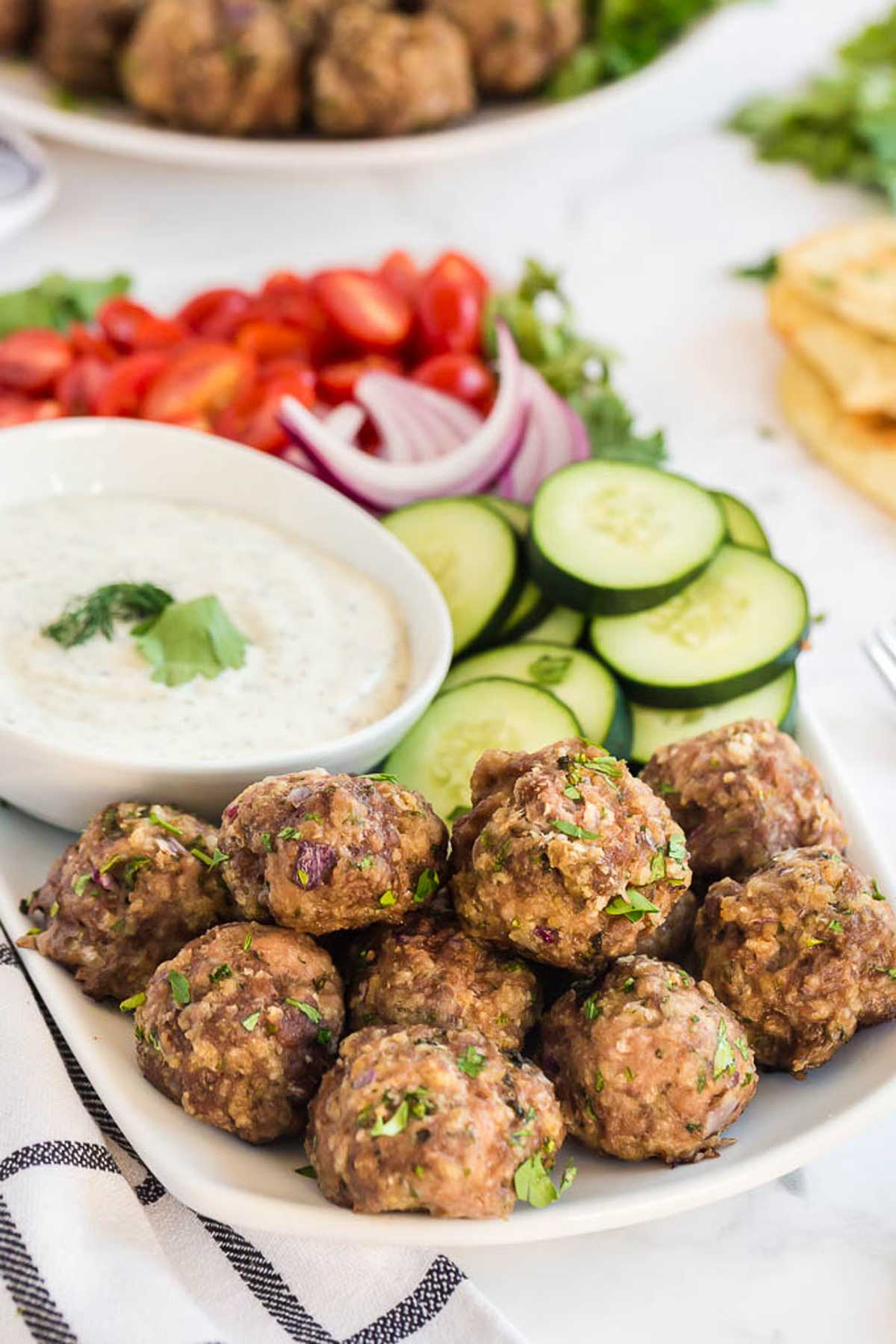 Baked Greek meatballs served with tzatziki sauce and sliced cucumbers