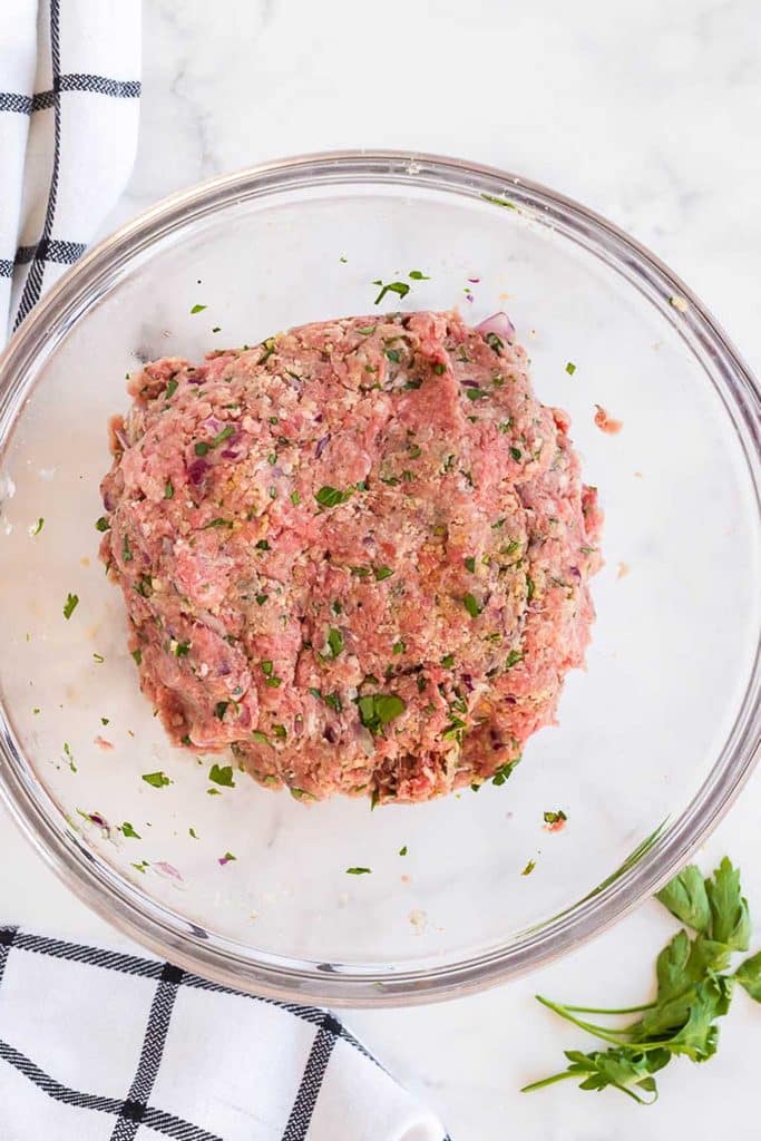 ground beef, ground pork onion, herbs and spices mixed in a glass bowl
