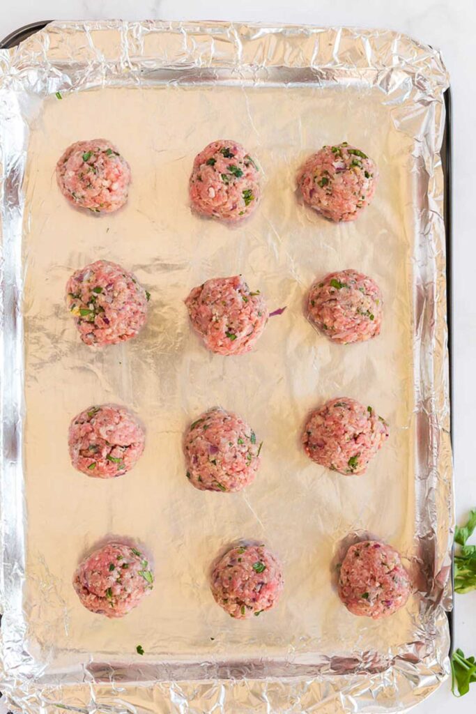 Greek meatballs ready to bake on a sheet pan
