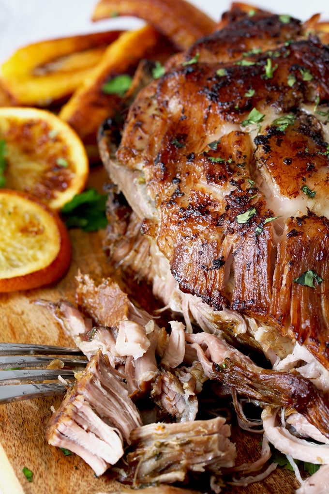 Tender Cuban Mojo Pork shredded with a fork on a cutting board.