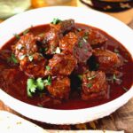 Chunks of beef in authentic Chile Colorado sauce served in a white bowl.