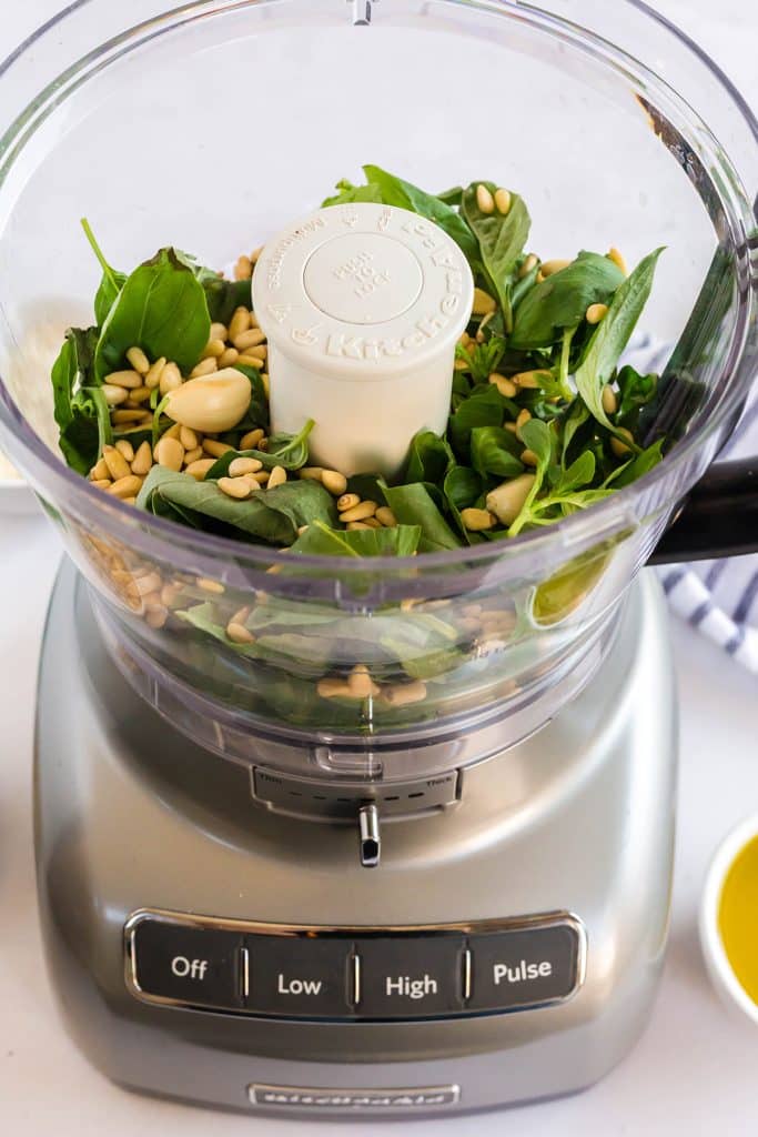 all the ingredients to make pesto in a food processor