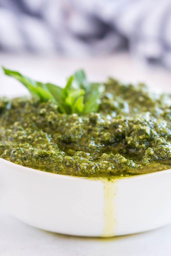 A white bowl overflowing with freshly made basil pesto.