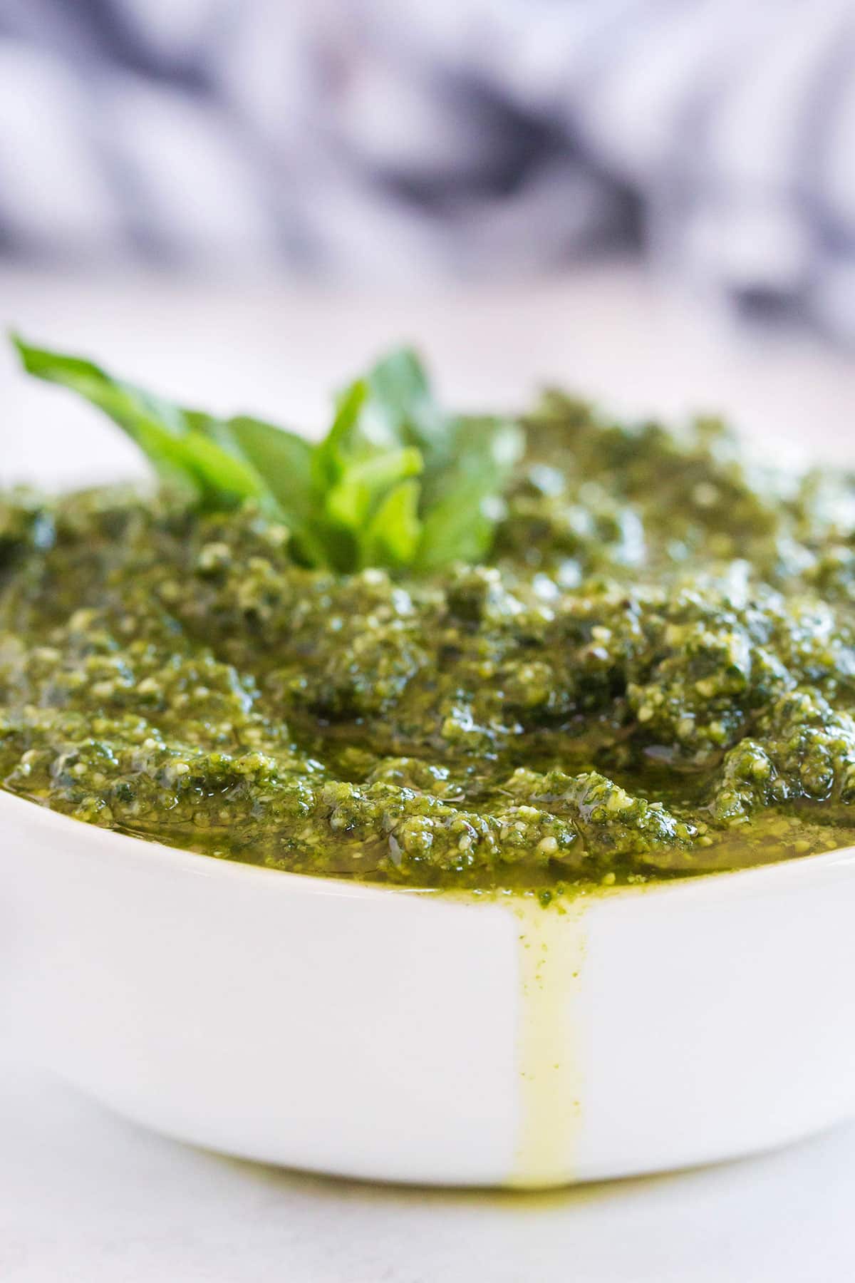 A white bowl overflowing with freshly made basil pesto.