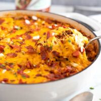 Cheesy pasta bake scooped from a white skillet.