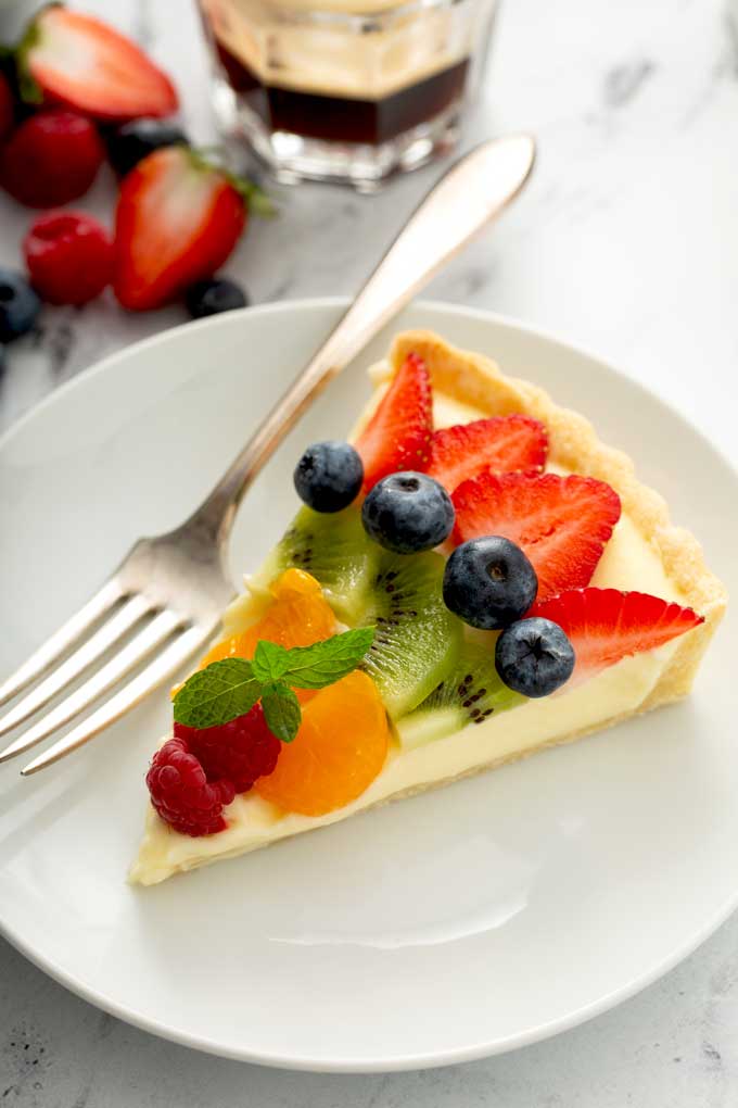 A slice of the best fruit tart on a white plate.