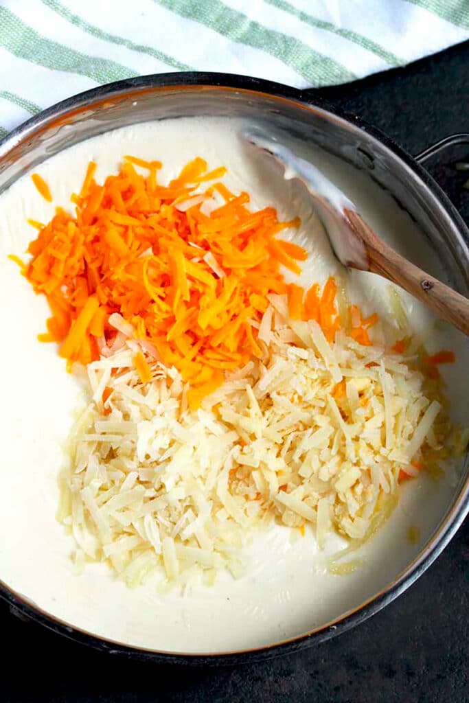 Picture here a pot with bechamel sauce topped with three types of shredded cheese.