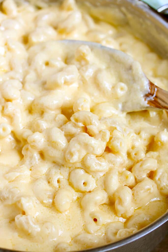 Creamy macaroni pasta and cheese sauce tossed in a large saucepan.