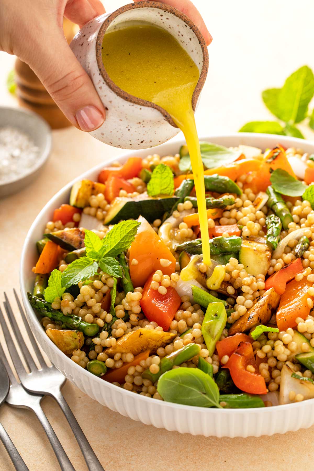 A white bowl filled with couscous salad and grilled veggies.
