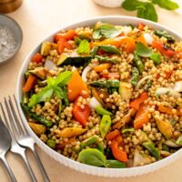 Pearled Israeli couscous salad with grilled seasonal vegetables in a white bowl