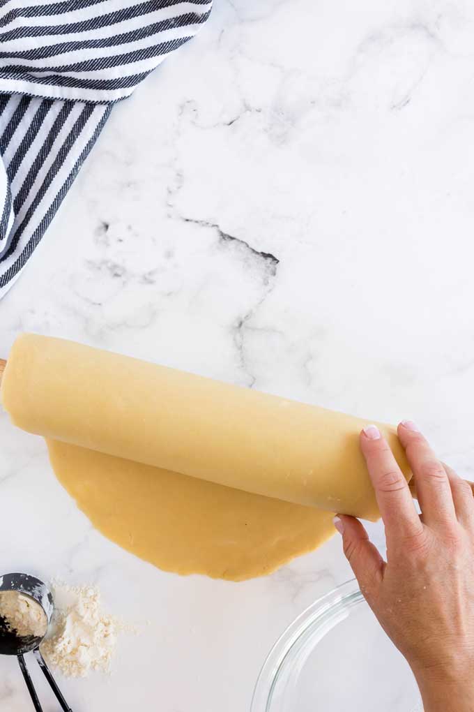 Rolling pie dough on a rolling pin to transfer it to a pie plate.