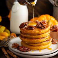 Stack of pumpkin pancakes drizzled with warm maple syrup