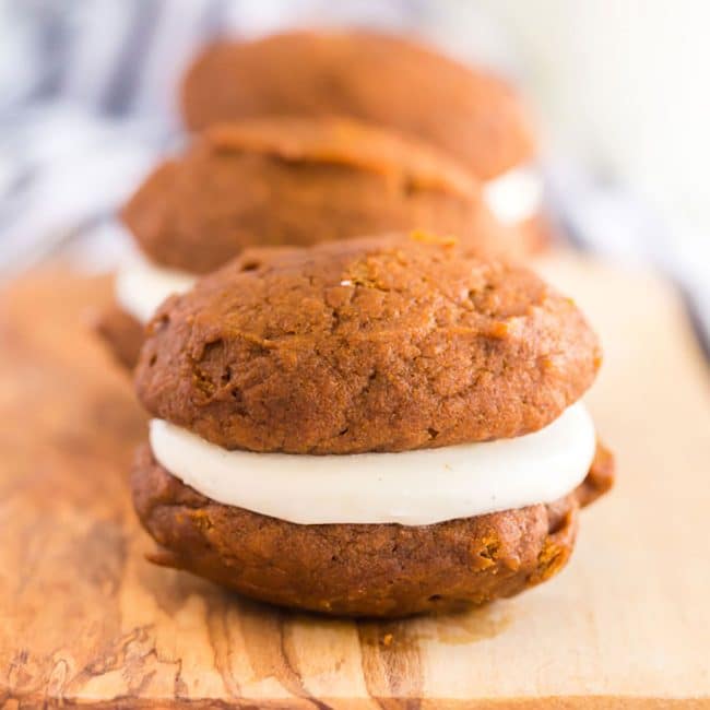 Close up of a pumpkin whoopie pie filled with cream cheese frosting.