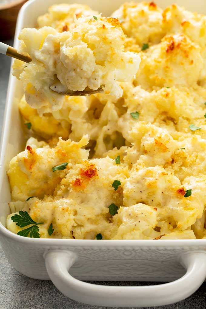 Cheesy Cauliflower getting scooped from a casserole.