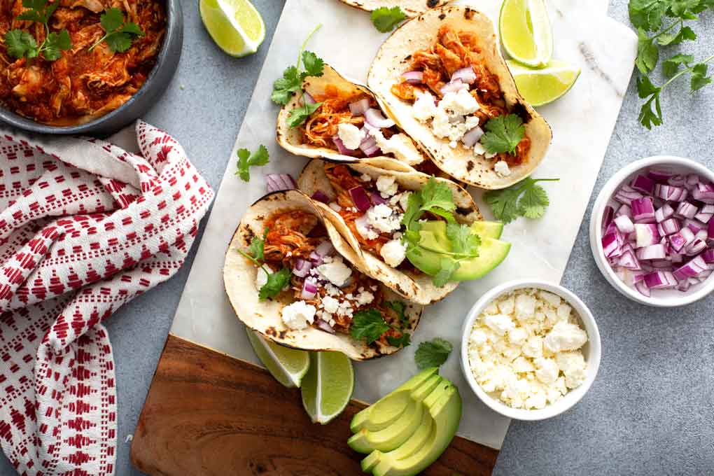 Top view of Mexican chicken tacos tinga with all the fixings .