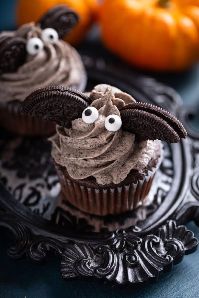 Oreo cupcake with cookies and cream frosting decorated with oreo cookies and candy eyes to resemble a bat.