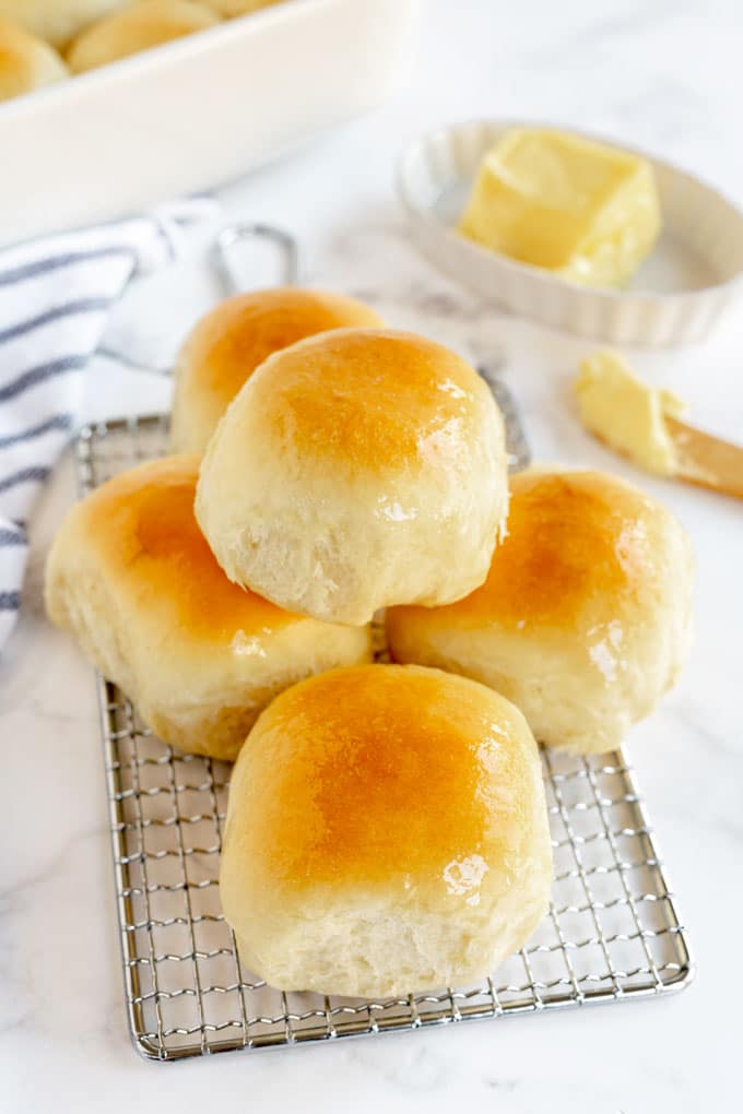 Dinner rolls brushed with butter on a cooling rack.
