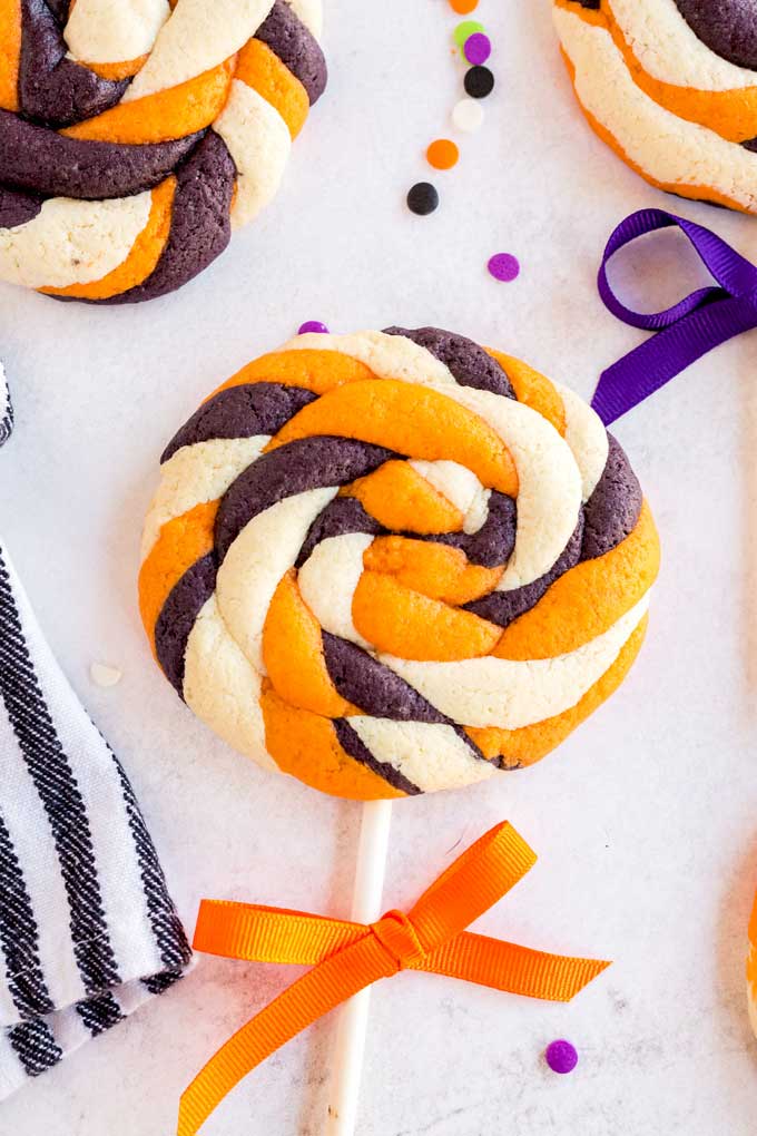 White, orange and black lollipop cookies on a white surface
