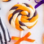 Pin image of a halloween white, orange and black cookie in a lollipop shape