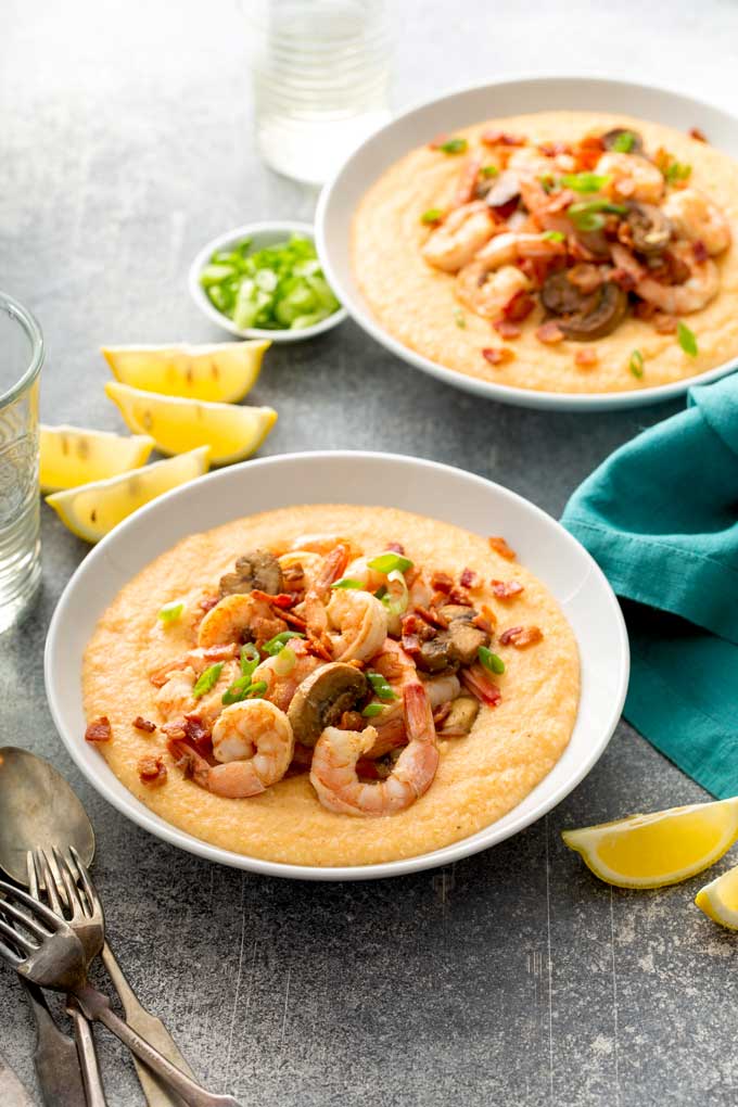 Two bowls filled with creamy grits and shrimp.